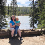 Amanda and Camille sitting on a log in front of a river in yellowstone national park
